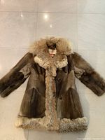 Front view of the full coat showing the soft brown fur and button closure