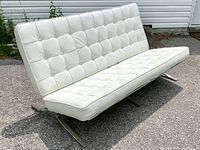 Front angled view of sofa showing tufted cushions and chrome x-frame legs