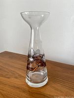 Full view of tall clear art glass vase on wooden surface with colored glass detailing