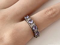 Photo of the ring worn on a finger showing the arrangement of purple and clear stones