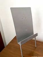 Front angled view of the vintage metal art stand showing flat back panel and ledge.