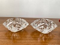 Pair of vintage crystal candle holders shown side by side on wooden surface, clear faceted crystal with boat-like shape