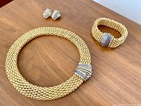 Full view of necklace, bracelet and earrings set arranged on wooden surface