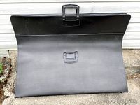 Full view of large black portfolio folder showing size and clasp closure.