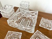Photo showing the large square crystal bowl with several small square bowls stacked behind it and a few small bowls placed visibly in front.