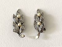 Pair of vintage Tortolani silver-tone metal clip-on earrings shaped as leafy branches, each with two faux pearls.