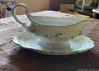 Side angled view of Johann Haviland blue garland gravy boat on matching underplate showing handle, spout, and floral pattern.