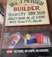 Wooden builder sign with painted text in green and red lettering advertising Wm. J. McHugh Builder including Ocean City and Ridley Park, PA phone numbers and a mailing address.