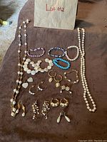 Jewelry lot showing multiple necklaces, bracelets, earrings including pearl and bead varieties in gold-tone settings.