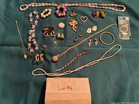 All jewelry pieces laid out on dark green fabric showing the full lot.