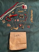 Full lot of assorted women's vintage jewelry pieces arranged on dark green fabric, containing necklaces, earrings, bracelets, brooches, and rings in red, white, and gold tones.