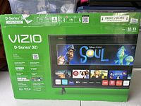 Front side of the green box displaying Vizio brand, model D-Series 32 inch, and key features including 1080p Full HD resolution and smart TV apps.