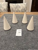Four cream-colored ceramic trees arranged on a gray fabric surface showing their shape and height relative to chair backs and table.