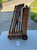 Side front view of croquet set on metal stand showing mallets and balls with visible brand name.