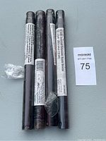 Four rustic bronze fan downrods laid together on a gray surface with labels visible, showing their length and finish.