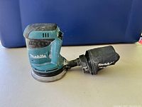 Side view of Makita cordless random orbit sander showing dust collection bag attached.