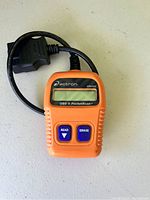 Front view of orange Actron CP9125 PocketScan OBD II code reader showing screen and buttons.
