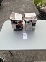 Two Ridgid VF7000 wet pick-up foam filters in original boxes placed on a table outside, boxes show wear.
