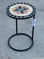 Full view of the metal side table showing the circular metal base and a round ceramic mosaic top with geometric star pattern.