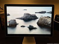 Front view showing the 24-inch Cinema Display screen with a scenic wallpaper image of large rocks and calm water.