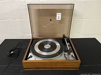 Front view of Dual 1219 turntable on walnut veneer plinth, dust cover open