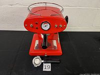 Red espresso machine front view with portafilter and filter baskets on black background