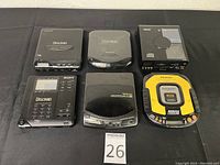 Top view showing full set of six portable CD players on black surface with lot marker
