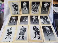 Set of 12 black and white bee hive style vintage photos of hockey players in Detroit Red Wings uniforms laid out on table.