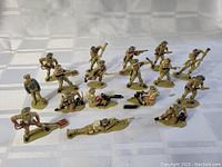 Full set of 17 painted British 8th Army toy soldiers from the 1950s arranged on a white surface. Various poses including shooting and marching.