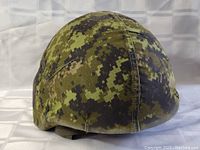 Front and side view of Canadian military helmet covered with digital camouflage fabric cover, showing good condition and secure fit.