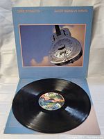 Vinyl record disc with colorful label in the center, laid on top of inner cover sleeve