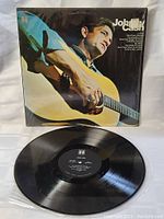 Vinyl LP record removed from sleeve, black vinyl disc in protective sleeve on white background.