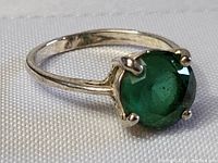 Close-up view of the vintage sterling silver ring with round green stone showing ring band detail and prongs.