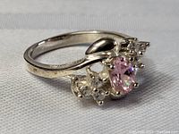 Front-side view of the sterling silver ring displaying the oval pink topaz center stone and accent clear stones, showing setting details.