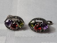 Front view of the pair of vintage earrings showing green, red, and purple stones with marcasite detailing