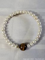 Top-down view of circular pearl and tiger's eye bead bracelet showing overall design and bead arrangement.