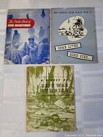 Three vintage World War II themed books laid out flat on a surface showing covers.