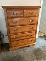 Full front view of the 6-drawer wooden dresser showcasing brass handles and oak finish.