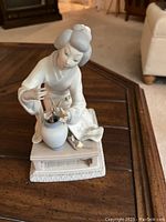 Full front view of the porcelain Geisha flower arranging statue on a carved base