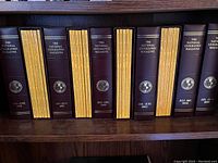 Photo showing multiple volumes of National Geographic magazines in dark brown leather binders with gold embossed titles and logos on shelves.