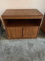 Front view of wooden TV tabletop cabinet showing open shelf and two closed front panels on lower section.