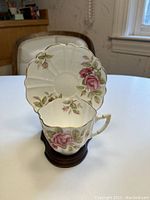 Cup and saucer set displayed on table, showing floral design and scalloped edges