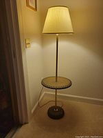 Full view of the vintage corner floor lamp with round center table and fabric lampshade lit, showing overall design and placement in corner.