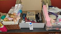 View of Barbie dolls lying on white cushioned wicker basket seat next to box containing model train parts and other toys