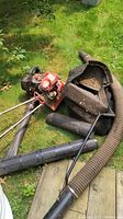 Top view showing the red tiller engine, black blower housing, and attached flexible tubes on grass.