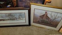 Two framed prints on floor against wall: one black framed print 22x28, one gold framed print 30x25 showing snow barn scenes