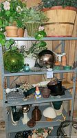Full view of metal shelving unit filled with garden decor items such as pots, garden spheres, figurines, and plants. Shows placement of items and condition of shelving.
