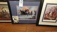 Partial view of framed print depicting soldiers in battle using bayonets with title mentioning Gettysburg and battle date.