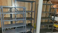 Five metal shelving units seen from the side, showing adjustable shelves and metal frame.