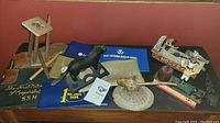 Wide view showing all items together on a table: metal banks shaped like a horse and fire truck, wooden nutcracker, and several bank document bags.